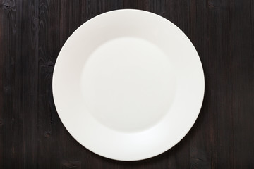 top view of white plate on dark brown table