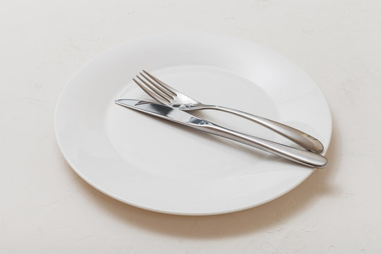 white plate with parallel knife, spoon on white