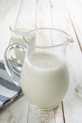 fresh milk in glass jug and glass on wooden background