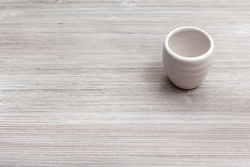 white cup for sake on gray brown wooden board