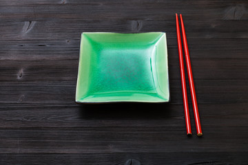green saucer and chopsticks on dark brown table
