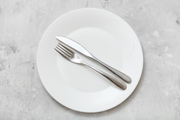 top view of white plate with flatware on concrete