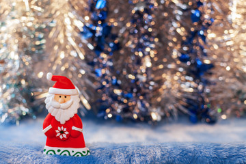 Figurine toy Santa Claus on Christmas colorful bokeh background.