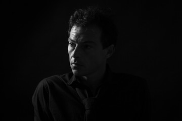 Man low key high-contrast profile portrait in backlight with a serious look on his face
