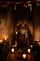 Medieval king on throne in ancient castle interior.