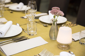 Empty menu paper beside prepared plate with flower and glasses