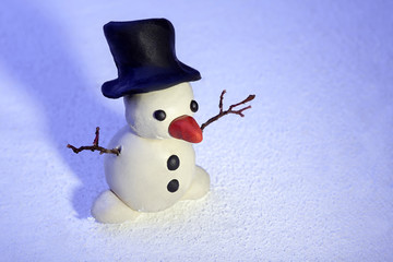 little snowman made of plasticine standing on real snow