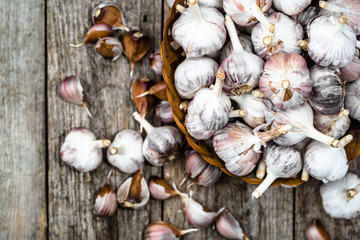 Fresh garlic in the basket, top view. Farm vegetables on wooden table.