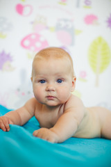 Plump child holds blue blanket in his tiny arms