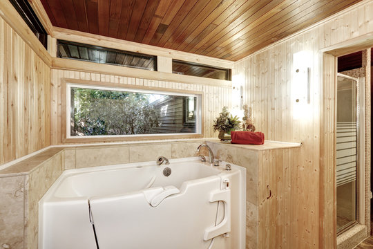 White bath tub in wooden paneled bathroom