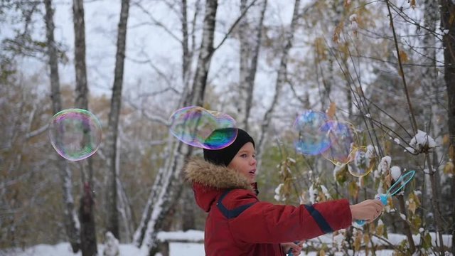 boy makes big soap bubbles in the Park with delight