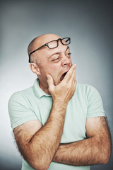 Closeup portrait of sleepy tired man, placing hand on mouth yawn