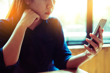Charming beautiful woman using smartphone in coffee shop cafe.