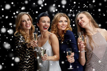 happy women with champagne glasses over black