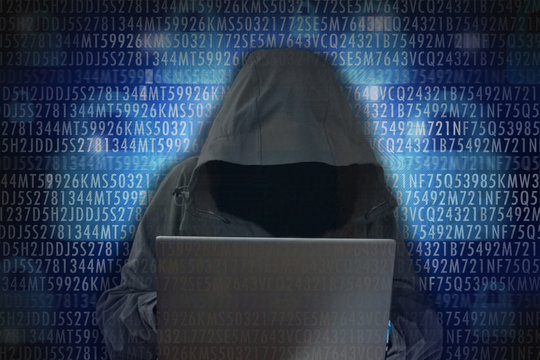 Unrecognizable hacker in front of computer – cybercrime concept