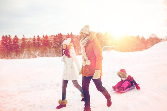 Happy Family With Sled Walking In Winter Outdoors