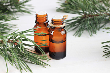 Dark glass bottles with pure aroma oil. Green Pine branches. Natural remedy. 
