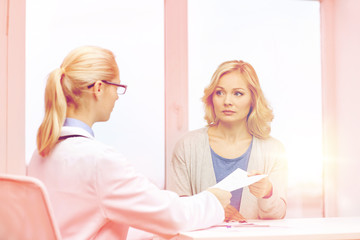 doctor giving prescription to woman at hospital