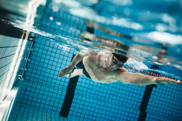 Young man swimming the front crawl in a pool.
