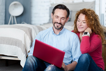 Couple sitting on floor and using laptop