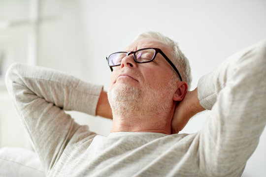Senior Man In Glasses Relaxing On Sofa