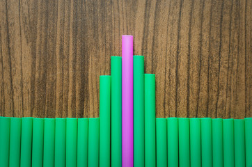 difference pink and green drinking straw on wood board, leader chief concept