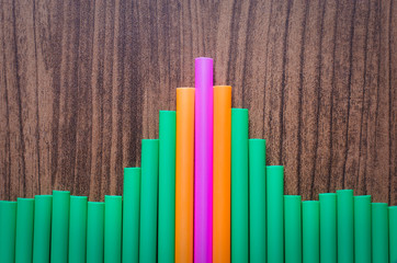pink orange and green drinking straw with shaped plane on wood board, concept to flying go to success, leader chief concept