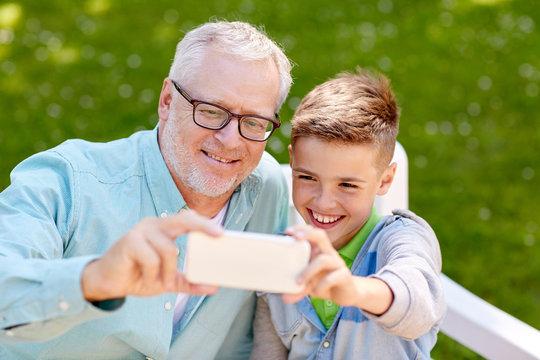 old man and boy taking selfie by smartphone - Powered by Adobe