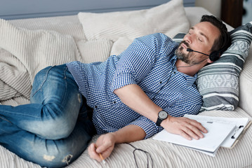 Bearded man with headphones sleeping on couch