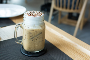 A glass of ice cappuccino art with foods on table