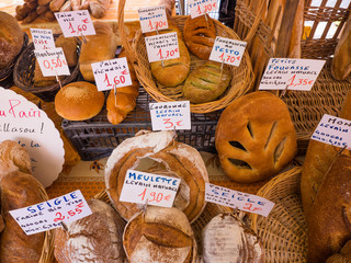 Artisan French breads in local outdoor market in France with description and prices in euros.