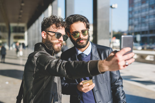 Two young bearded man outdoor in the city taking selfie - social network, technology, friendship concept
