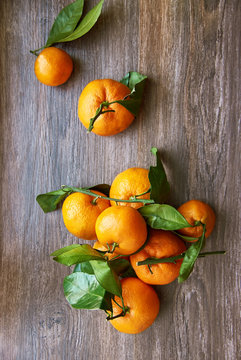 Still life of ripe tangerines with branches on a wooden table. Top view