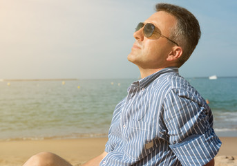 Man is sunbathing on sea coast, summer nature outdoor. Portrait