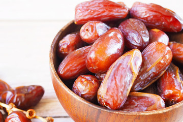 Close up of a bowl of dried dates on a wooden background.