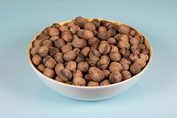 walnuts in a round white plate on a blue table