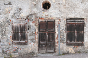 old weathered facade with a door and two Windows