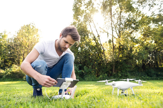 Young hipster man with drone. Sunny green nature.
