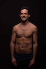 Obraz na płótnie Canvas dark moody nude smiling happy shirtless abs young man portrait