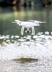 Drone quadcopter with camera flying above water.