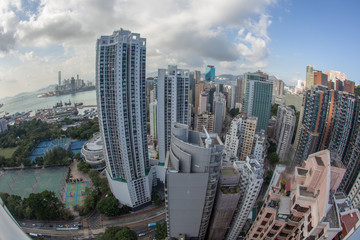 Obraz premium Wide angle shot of Hong Kong in daytime. Clouds sailing over the city with high-rise architecture, harbour with dockyard in background