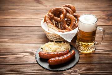 Pretzels, bratwurst and sauerkraut on wooden table