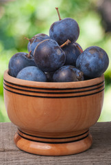 blackthorn berries in a wooden bowl on table with blurred background