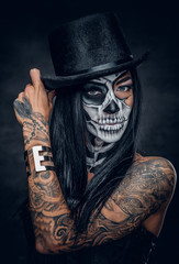 A woman with skull make up in top hat on Halloween.