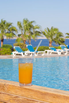 glass of mango juice with a straw on a background of sea and pal