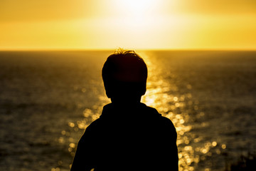 Silhouette of a teenager boy on sunset