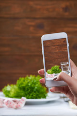 Women takes photo with smarphone with diet concept on screen. Diet concept. Fresh salat, water and measurement tape - diet and healthy eating concept. On a wooden background. Shooting for social media