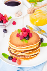 Stack of delicious american pancakes with berries on a white background