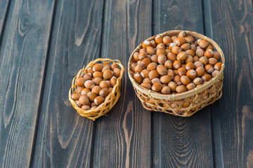 Hazelnuts in two straw baskets  on dark rustic wooden background