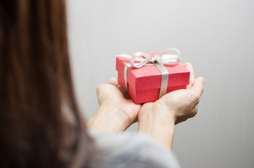 Closeup, Woman hand holding red gift box, female giving gift, New year holidays and greeting season concept, Rear view.